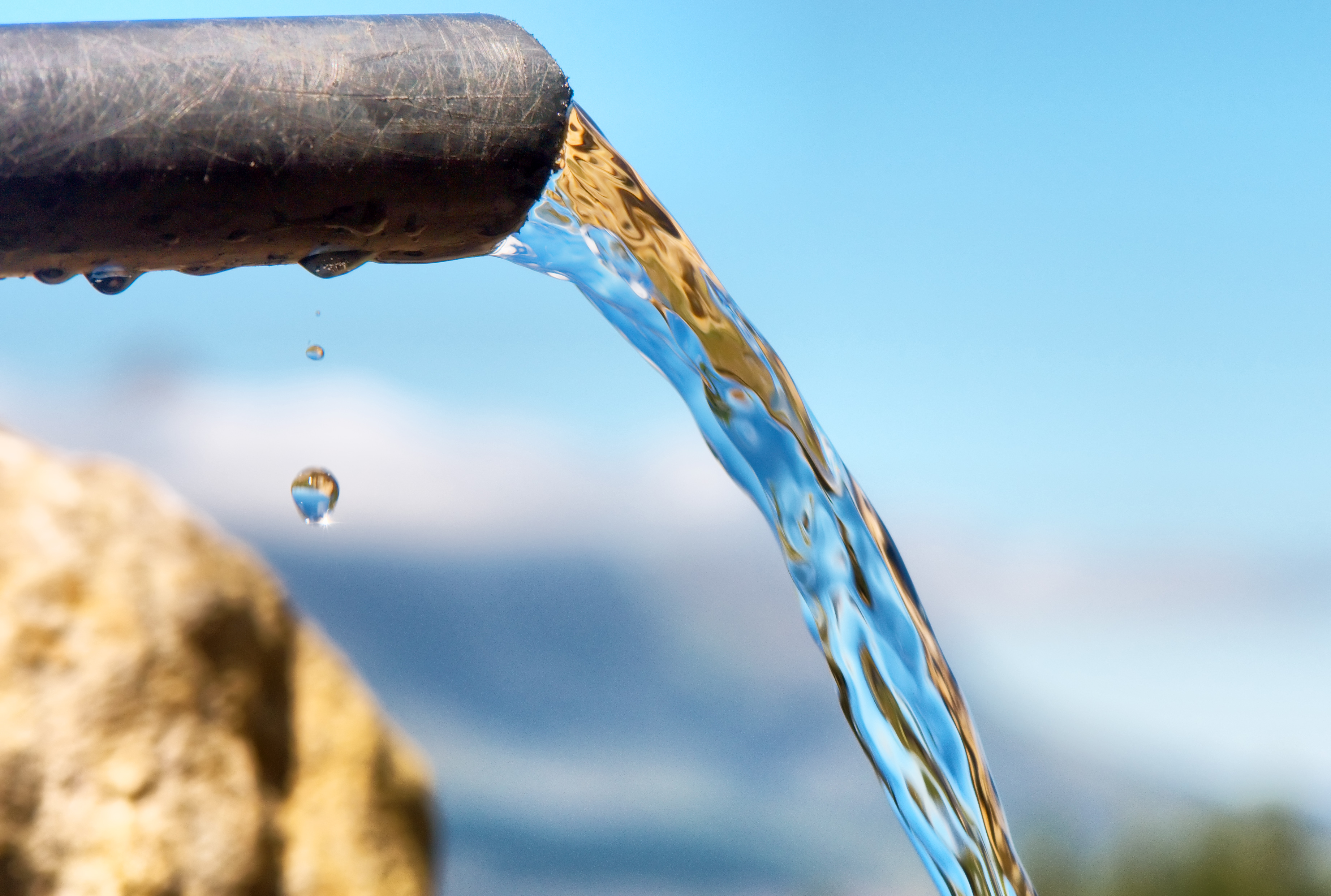 Water flowing from pipe against blurred mountains