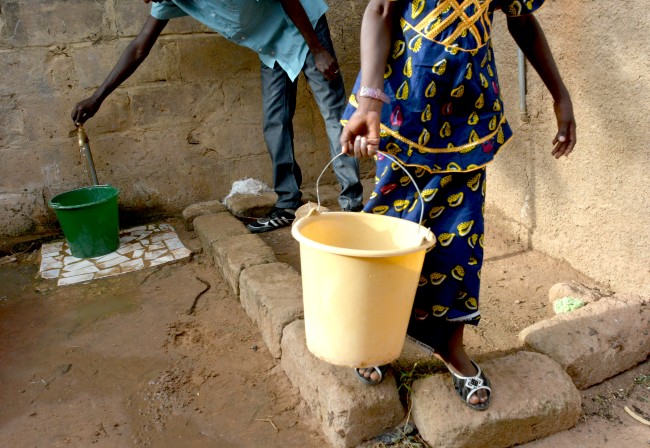 man and woman filling buckets with water from a standpipe in Africa