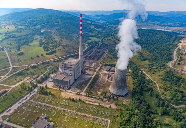 aerial view of thermal power station in green countryside, showing tall steam tower